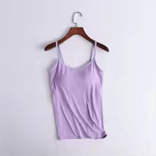 A light purple/lavender camisole tank top hanging on a wooden hanger against a plain white wall.